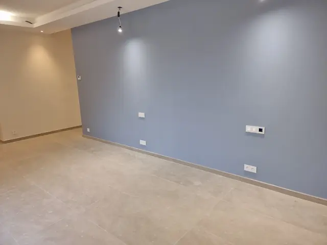 Chambre avec mur bleu et éclairage sur rail