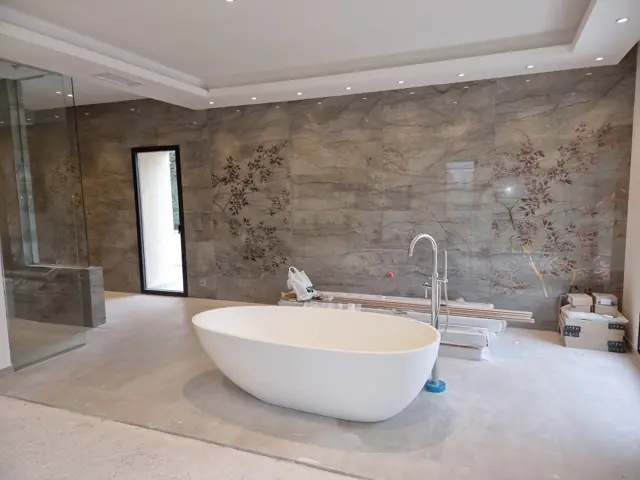 Salle de bain avec baignoire îlot et mur en pierre